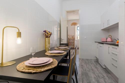 a kitchen with a table with chairs and a kitchen with white cabinets at Cozy Apartment with Patio near Carcavelos Beach in Carcavelos
