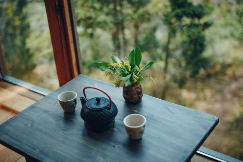 une table avec deux tasses et un vase avec des fleurs dans l'établissement Üügumetsa treehouse, à Kallaste