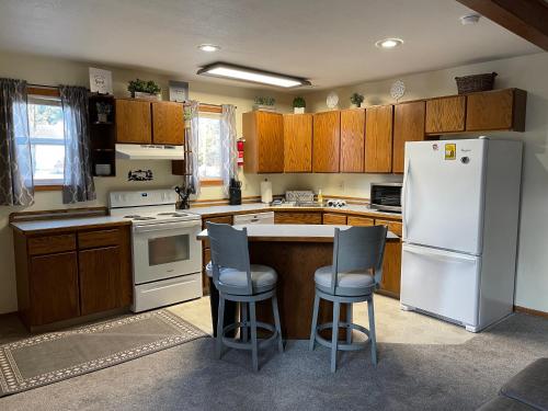 eine Küche mit einem weißen Kühlschrank und 2 Barhockern in der Unterkunft Den Mishka - Kodiak's Den of the Little Bear in Kodiak