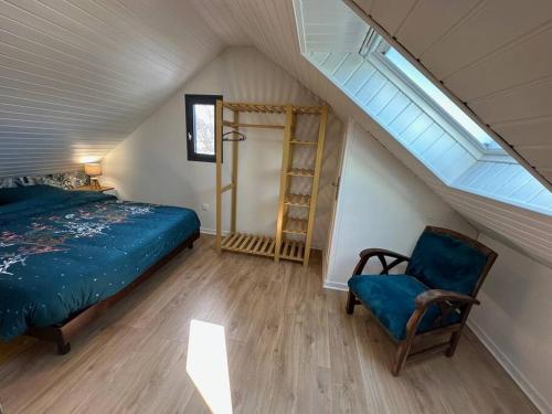 une chambre avec un lit et une chaise dans un grenier dans l'établissement La maison de la plage, 600m de la plage, Formule tout inclus, à Erdeven