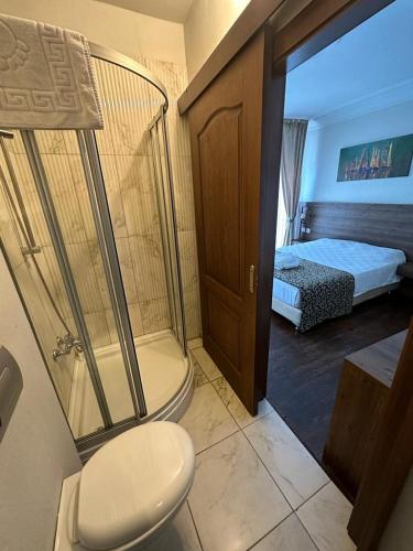a bathroom with a shower and a toilet and a bed at Paperon Butik Otel in Limonlu