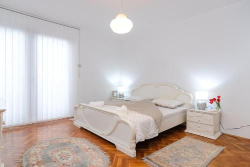 a white bedroom with a white bed and a rug at The Cosmic Gate Apartments in Visoko