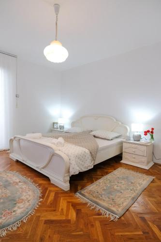 a bedroom with a white bed and a wooden floor at The Cosmic Gate Apartments in Visoko