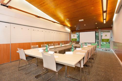 a conference room with tables and chairs and a whiteboard at Holiday Inn Lille Ouest Englos by IHG in Englos