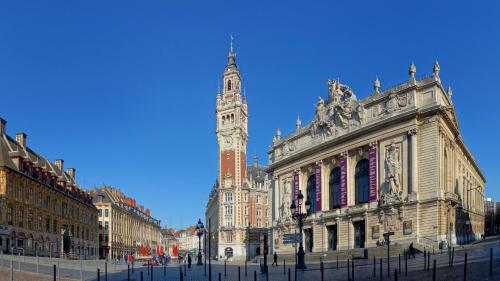 a large building with a clock tower in a city at Holiday Inn Lille Ouest Englos by IHG in Englos