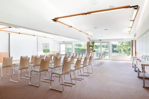 an empty room with chairs and tables and windows at Holiday Inn Lille Ouest Englos by IHG in Englos