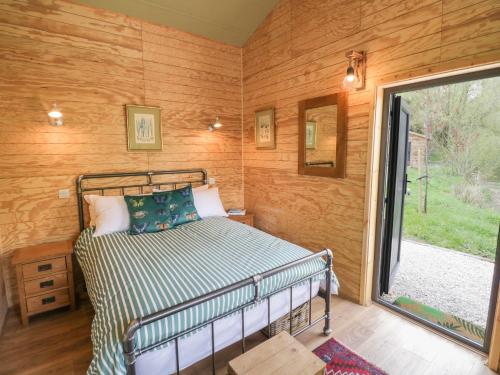 a bedroom with a bed in a room with wooden walls at Dragonfly in Rugby