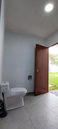 a bathroom with a toilet and a wooden door at Casa Jardín Real in Temixco