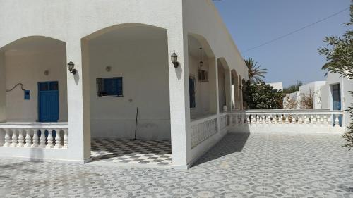 a courtyard of a house with white walls and a tile floor at Waneshouse دار الونس (Djerba) 