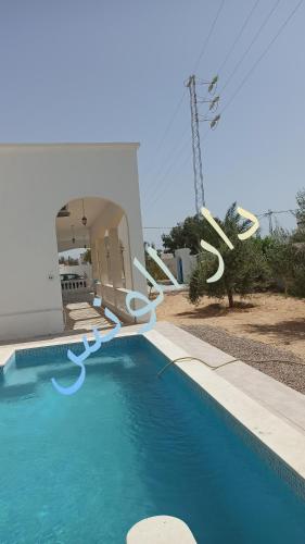 a swimming pool in front of a house at Waneshouse دار الونس (Djerba) 