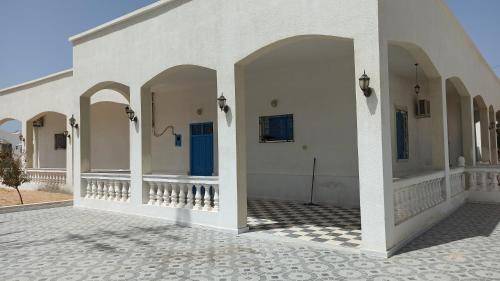 a white building with arches and a tile floor at Waneshouse دار الونس (Djerba) 