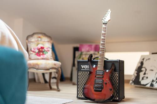 a guitar next to a speaker next to a chair at L'Avant Scène Meublé 5 étoiles Parking Gratuit Jacuzzi in Avignon