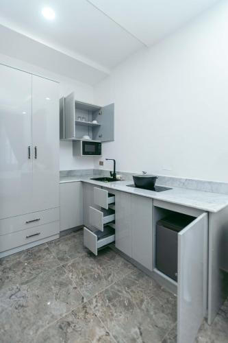 a kitchen with white cabinets and a sink at Phoenix Luxury Apartments in Abuja