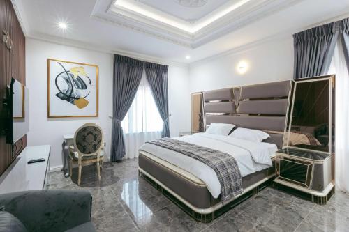 Phoenix Luxury Apartments في أبوجا: غرفة نوم بسرير كبير وكرسي