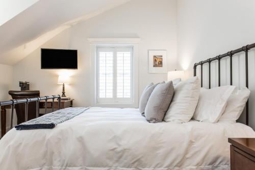 a white bedroom with a large bed with white pillows at Crestwood at Oak Street Mansion in Kansas City