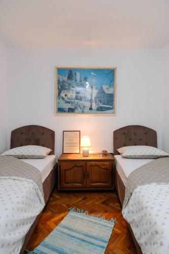 a bedroom with two beds and a table with a lamp at The Cosmic Gate Apartments in Visoko