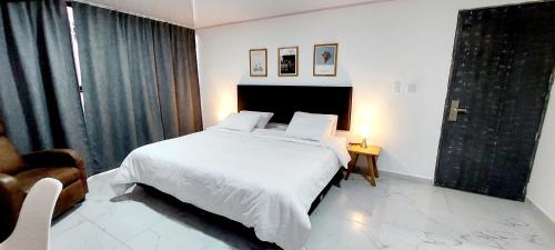 a bedroom with a white bed and a chair at HOTEL A & A SANTA ALEJANDRIA in Medellín