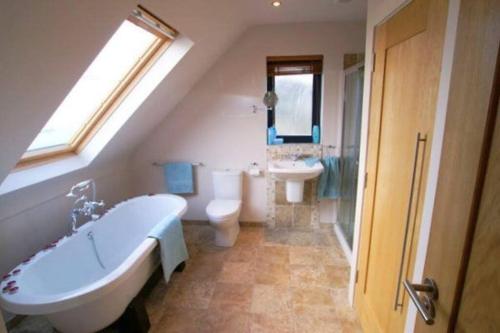 ein Badezimmer mit einer Badewanne, einem WC und einem Waschbecken in der Unterkunft An teach Illanmore in Portsalon