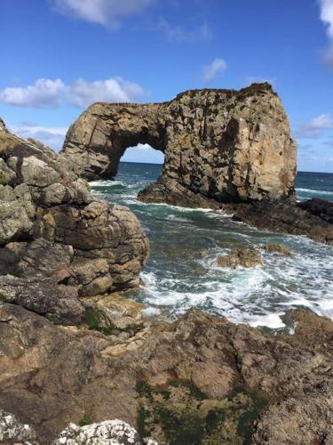an arch in a rock formation in the ocean at An teach Illanmore in Portsalon