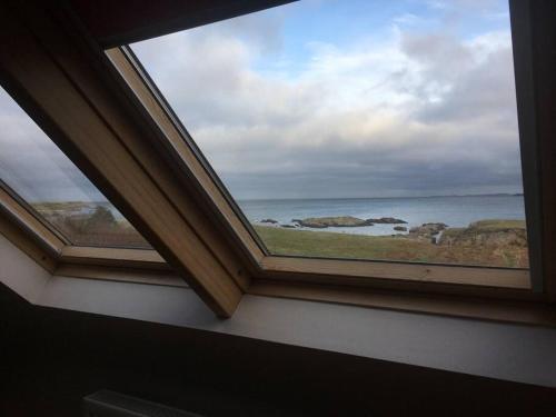 a window in a room with a view of the ocean at An teach Illanmore in Portsalon