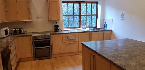 a kitchen with wooden cabinets and a stove top oven at The Den, Coves House in Wolsingham