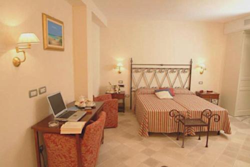 a bedroom with a bed and a desk with a laptop at Relais Sant'Eligio in Ostuni