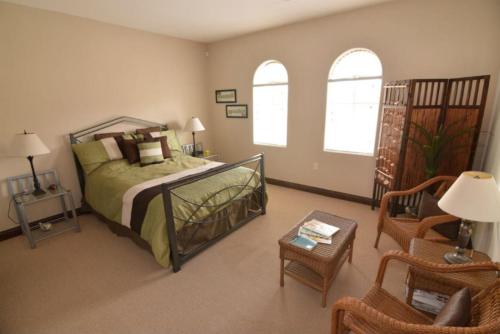 a bedroom with a bed and a chair and windows at El Dorado Paradise #434 in San Felipe