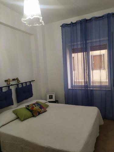 una camera da letto con un grande letto bianco con tende blu di Al Papergatto a Messina