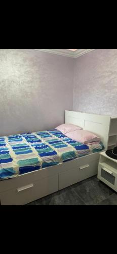 a bedroom with a bed with a blue and white comforter at Appartement alouer proche aquapark park Dar Bouazza in Casablanca