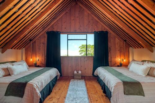 two beds in a room with a large window at The Red Door Mountain Cabin in Guadalupe