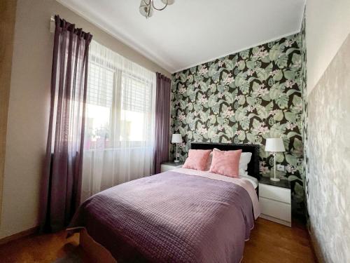 a bedroom with a large bed with pink pillows at Apartament Zdrojowy 62 K in Nałęczów