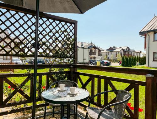 a table and chairs on a balcony with a view of a yard at Apartament Zdrojowy 62 K in Nałęczów