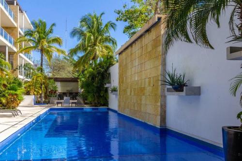 a pool in the backyard of a house with palm trees at Cozy 1be/1ba on 12 street gym+pool+100mbps internet in Playa del Carmen