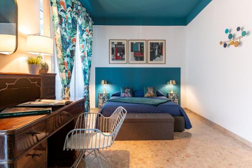 a bedroom with a blue bed with a desk and a chair at Libertà #102 - Guest House Palermo in Palermo