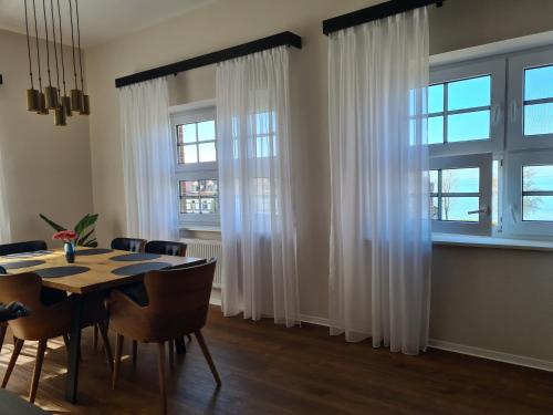 a dining room with white curtains and a table and chairs at Residence Black Eagle Lubmin Strand in Lubmin