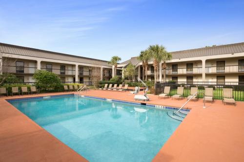 a pool in front of a hotel with chairs at Days Inn by Wyndham Jacksonville Airport in Jacksonville