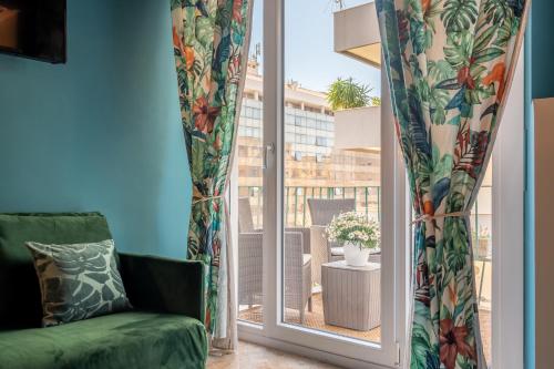 a living room with a green couch and a window at Libertà #102 - Guest House Palermo in Palermo