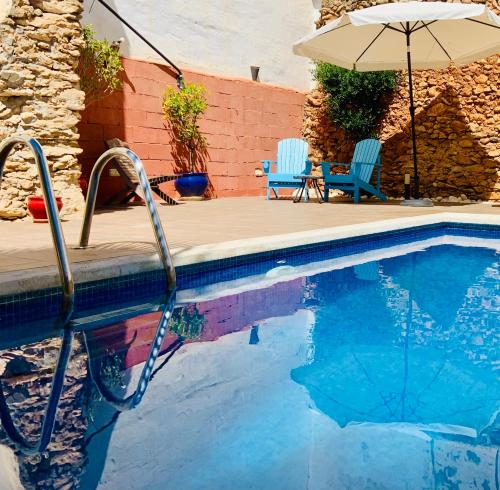 a swimming pool with two chairs and an umbrella at Boutique Hostal Lorca in Nerja