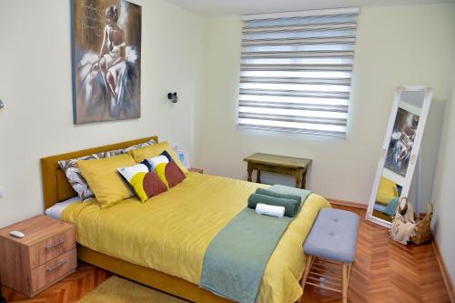 a bedroom with a bed with a yellow bedspread at Apartman Lenka in Arandjelovac