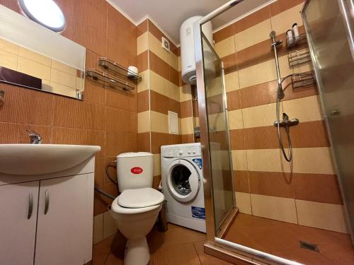 a bathroom with a toilet and a washing machine at Vqra Sarafovo in Burgas
