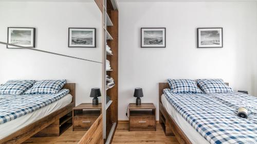 two beds in a room with white walls at BURSZTYNOVA Apartamenty Piamola in Kąty Rybackie