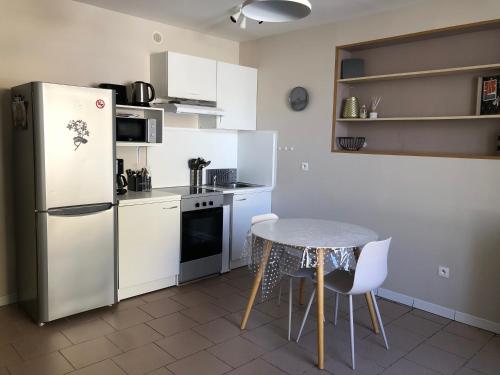 une petite cuisine avec une table et un réfrigérateur dans l'établissement T2 meublé pour curistes, vacanciers et stagiaires, à Rochefort