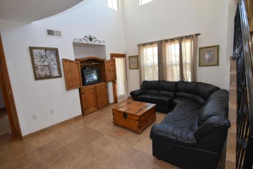 a living room with a black leather couch and a tv at 3-bedroom Poolside San Felipe Vacation villa in La Ponderosa