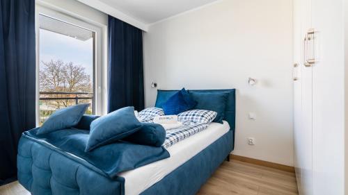 a bedroom with a blue bed and a window at BURSZTYNOVA Apartamenty Piamola in Kąty Rybackie