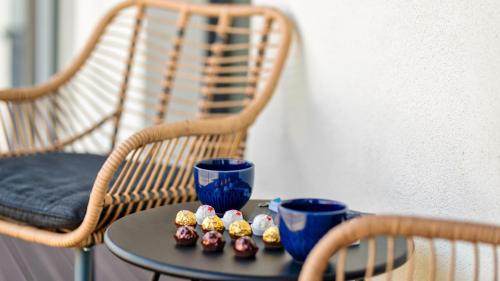 a table with two blue cups and muffins on it at BURSZTYNOVA Apartamenty Piamola in Kąty Rybackie