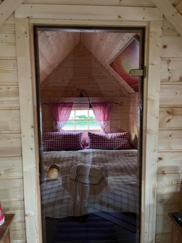 ein Schlafzimmer in einem winzigen Haus mit einem Fenster in der Unterkunft Grillkota Holzhütte in Lauenburg