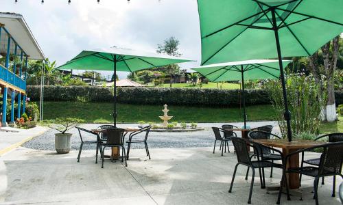 a group of tables and chairs with green umbrellas at Hotel Hacienda Santa Clara in Santa Rosa de Cabal