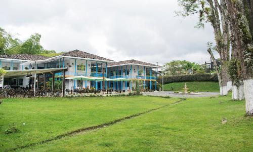 a large house with blue windows and a yard at Hotel Hacienda Santa Clara in Santa Rosa de Cabal
