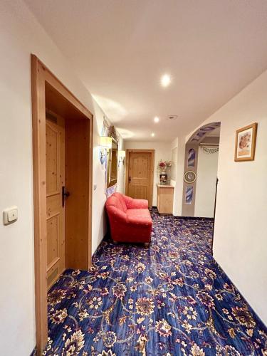 a hallway with a red chair in a room at Hotel Bergland in Grainau