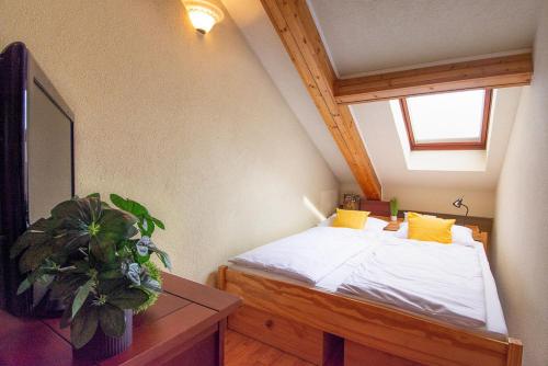 a bedroom with a bed with yellow pillows and a plant at Zsófia Apartman in Veszprém